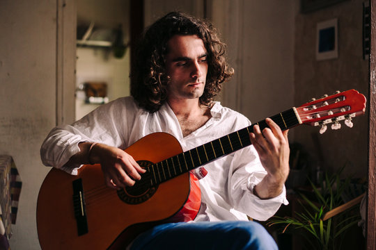 Young bohemian man playing acoustic guitar
