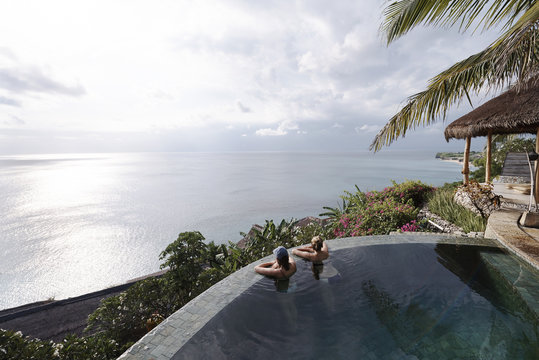 Two young attractive women relaxing in an infinity pool