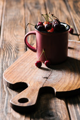 healthy tasty cherries in pink cup on wooden cutting board on table
