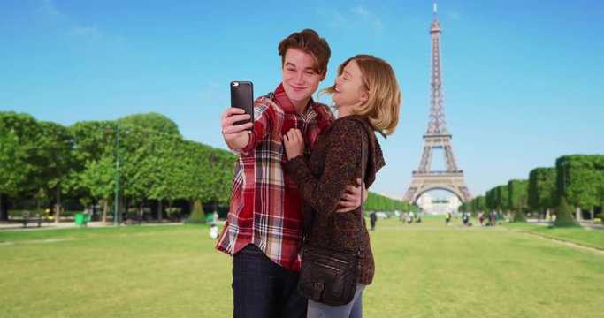 Cute millennial couple taking a selfie in front of the Eiffel Tower, Smiling male and female tourists taking picture for social media, 4k