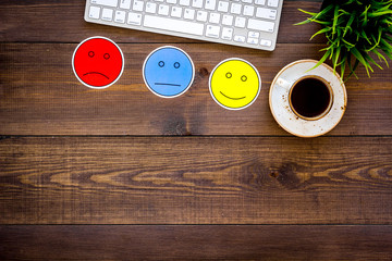 Customer satisfaction concept. Emoji smile, neutral, sad on work desk on dark wooden background top view copy space