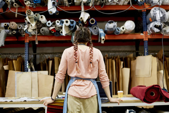 Female Worker Looking At Fabrics And Cardboard At Sofa Workshop
