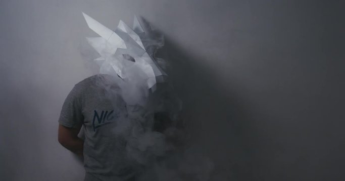 CINEMAGRAPH - SEAMLESS LOOP. Male wearing dragon head low poly paper craft mask exhaling smoke from a vapor. 4K UHD 60 FPS SLOW MOTION