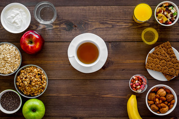 Set of products for healthy vegetarian breakfast. Fruits, oatmeal, yogurt, nuts, crispbreads, chia on dark wooden background top view space for text