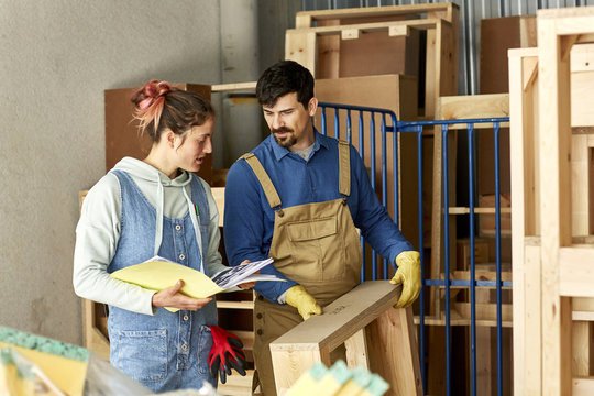 Worker Holding Wooden Frame While Discussing Over File With Coll
