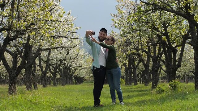 A young couple in love stroll together through a beautiful forest with their pet dog. In slow motion.
