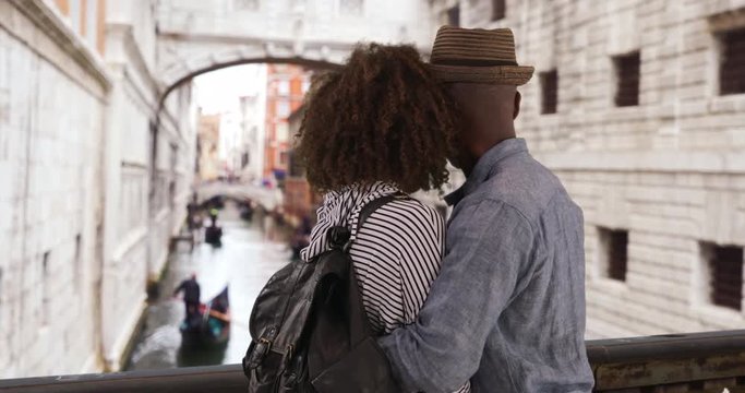 Happy millennial couple watch gondola boats on the Grand Canal, Black male and female hold each other and enjoy sights in Venice, 4k