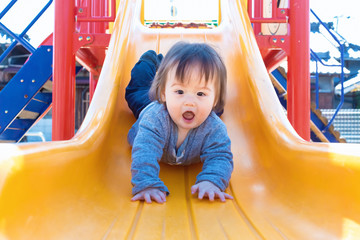 Mixed race toddler boy playing on a slide at a playground