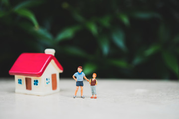 Miniature people, children standing on mini house and nature background using as family and relationship concept