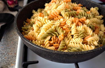 Fusilli (Fuso) - classic Italian pasta in the form of a spiral of durum wheat. Ingredient for cooking a traditional Italian dish. Cooking process. Soft focus, close-up. A place to copy.