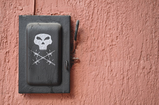 Old black switch, lever with painted skull over texture wall 