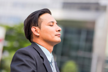 Asia young business man in front of the modern building in downtown .Concept of young  business people