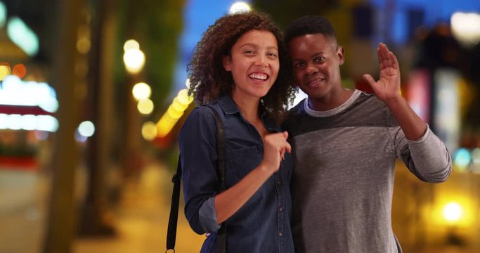 African American couple pose for portrait on the Champs-Elysees at night, Black man and woman smile and wave at camera on Paris street in evening, 4k