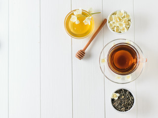 Freshly prepared tea with Jasmine flowers and honey on a white wooden table. Flat lay. Spring tea composition.