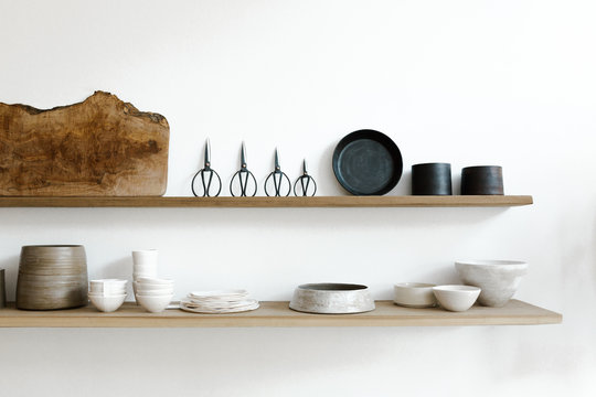 wood shelves of ceramics, scissors and cutting boards on white wall of curated shop
