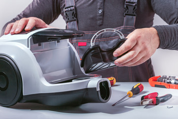 Man mechanic working in his workshop and repairing vacuum cleaner. Small business
