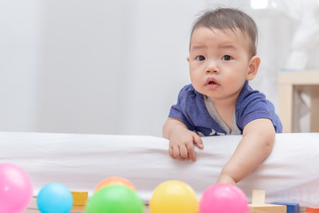 Fototapeta na wymiar Happy family concept,cute infant baby crawling on the floor at home, playing with colorful balls