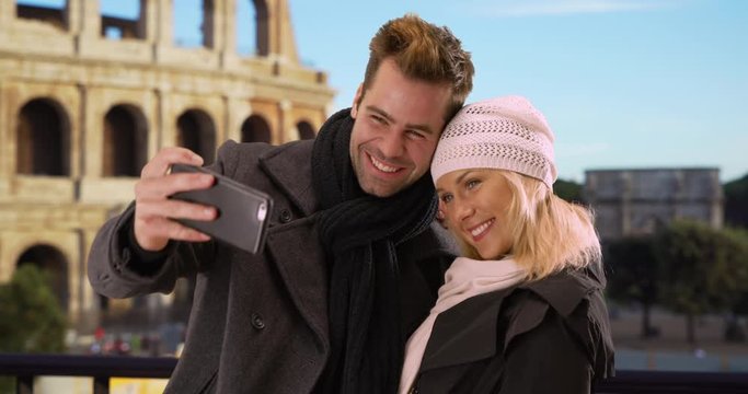 Attractive tourist couple in Rome taking a selfie, Caucasian man and woman take a picture together by the Coliseum, 4k