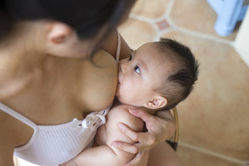Young asian mother breastfeeding her baby boy in home