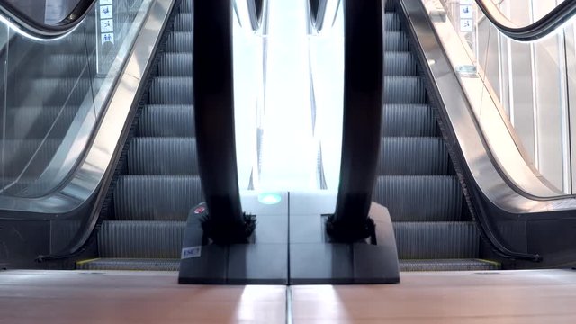 Young man walking down from modern escalator stairs. Moving staircase running up and down. urban lifestyle concept. 4K video