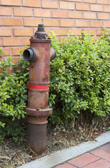 Red fire hydrant in retro style close-up against a brick wall
