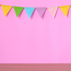 Colorful party flags hanging on pink background and wooden table, birthday, anniversary, celebrate event, festival greeting card background