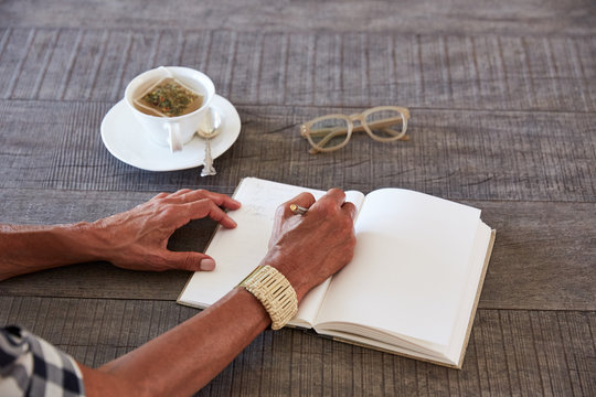 Senior African American woman drinking tea and writing in her journal