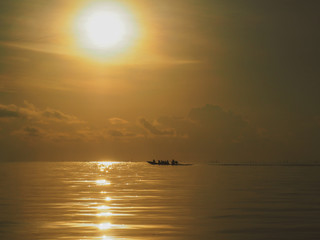 Sun over horizontal line and water with a littelboat, idyllic secenery.