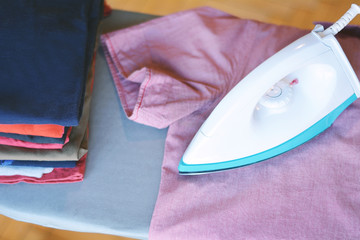 Close up view of man ironing blue shirt on ironing board
