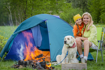 Family tourist near his camp tent at campfire with dog.