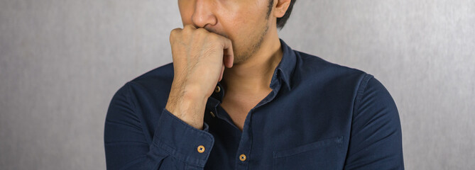 Fist on chin gesture by man on grey background