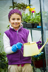 Beaitful child playing in greenhouse and care for plants. Cute girl engaged in gardening in the backyard. Spring organic growth concept.