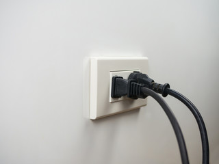 Electronics plugged in to the socket on white wall