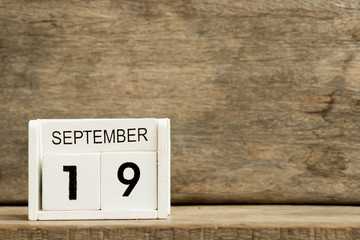 White block calendar present date 19 and month September on wood background