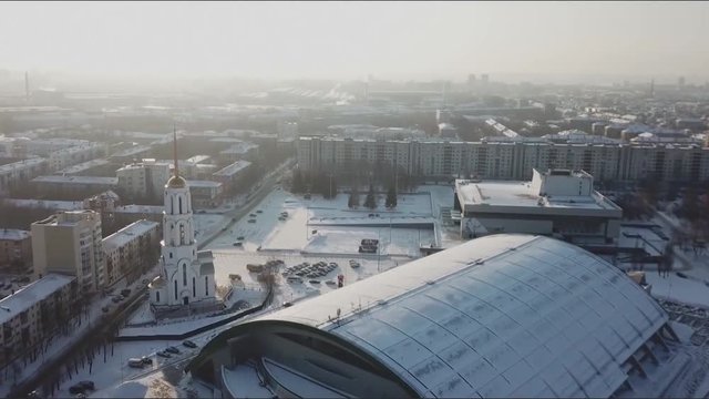 Aerial view of Church in Russia. Aerial view of an urban cityscape of a town with a crossing river in wintertime. Stock. White snow-covered roofs and snow all over the city.