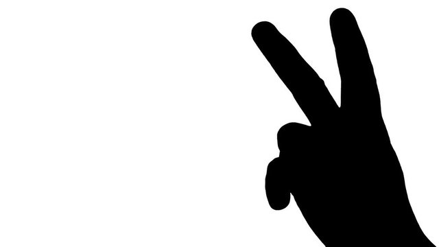 The fingers of a female hand creating the victory sign, showing the palm. Silhouette shot.
