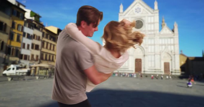 A Caucasian man picks up his girlfriend, Tourist couple playing on the street in Florence, smiling and laughing, 4k
