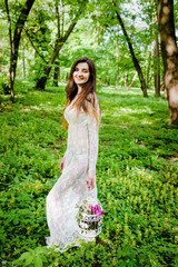 Pretty woman in a white dress holds a cage with flowers in her hands