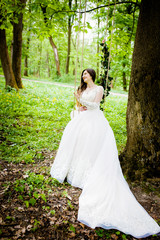 The bride is sitting on a swing decorated with flowers in the park