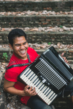 Asian man playing an accordion outdoor