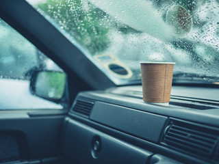 Paper cup of coffee on dashboard