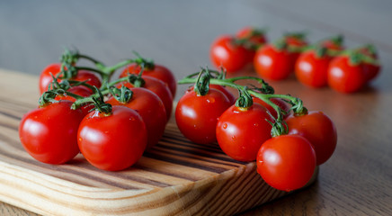 A branch of cherry tomatoes on wooden cutting board. selective focus