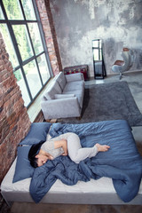 Naklejka premium Pain in stomach. Top view of beautiful unhappy woman lying on bed and touching belly