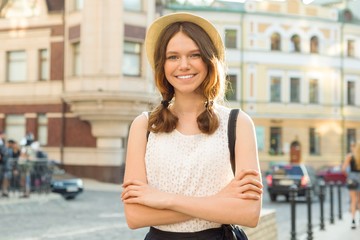 Outdoor portrait of teenager 13, 14 years old, girl with crossed arms, city street background