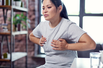 Complications of flu. Low angle of unhappy upset woman sweating and suffering from flu