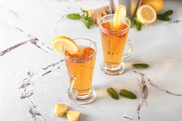 Glass cups of hot tea with ginger and lemon on table