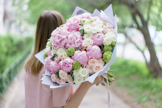 Young girl holding a beautiful spring bouquet. flower arrangement with hydrangea and peonies. Color light pink. The concept of a flower shop, a small family business