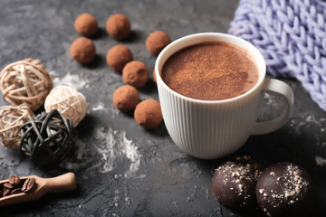 Cup of tasty hot chocolate and sweets on dark background