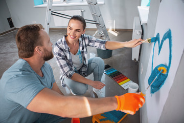 I treasure you. Inspired caring woman smiling at her man and they painting a heart with her man