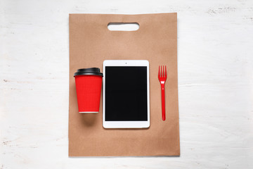 Composition with tablet PC and cup of coffee on wooden background. Food delivery